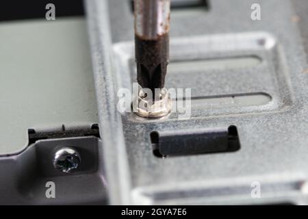 cacciavite che svita una vite di un pc sul lato del disco rigido Foto Stock