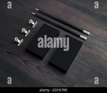 Cancelleria nera vuota di affari su sfondo di legno. Biglietti da visita vuoti, matite e graffette. Foto Stock