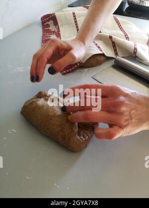 Le mani della donna impastano l'impasto per la cottura del pane di segale Foto Stock