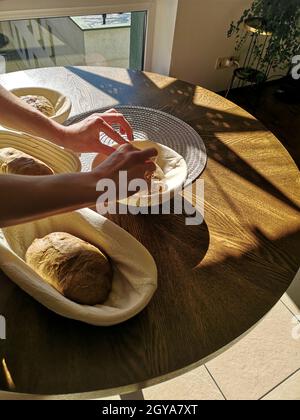 Il panettiere mette l'impasto di segale sulla pasta madre nei cestini Foto Stock