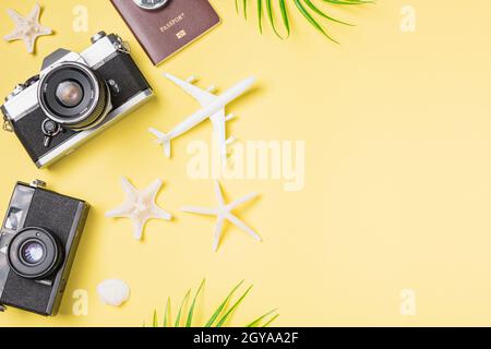 Flat Lay top view mockup retro fotocamera film, aereo, foglie, Starfish viaggiatore tropicale spiaggia accessori su uno sfondo giallo con spazio di copia, va Foto Stock