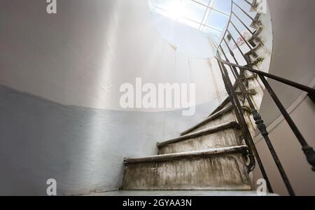 Antica scala a chiocciola con scalini in marmo e corrimano in ferro battuto. Luce naturale proveniente dal lucernario. Architettura e forma circolare Foto Stock