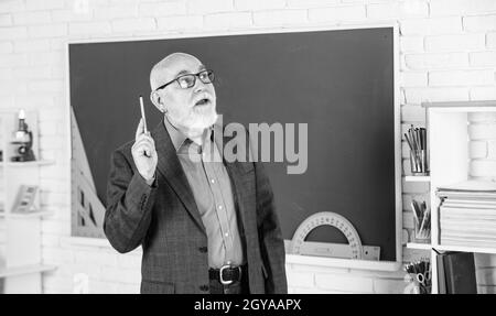 Condivisione delle conoscenze. Docente esperto. Insegnante maturo che gode di lavoro. Più strumenti introdotti nelle aule di tutti i giorni. Insegnante senior alla lavagna Foto Stock