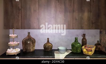 Grandi vasi di vetro, un cestino con mele e piatti all'interno di una cucina moderna. La combinazione di legno e calcestruzzo nel design. Moderna e polverosa Foto Stock