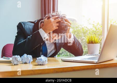 Giovane uomo d'affari asiatico stanco di non avere successo sul suo lavoro in scrivania tavolo ufficio Foto Stock