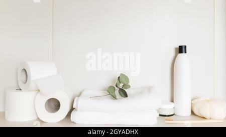 Lavabo in bagno bianco, ripiano con accessori da bagno. Concetto di pulizia dell'hotel. Concetto domestico. Panno, flacone di shampoo, crema per il corpo, punta bianca Foto Stock