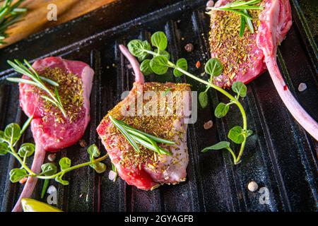 Costolette di agnello crudo condite e marinate con erbe Foto Stock