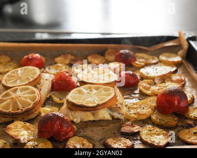 Filetto di merluzzo guarnito con timo, aglio e pomodori, preparazione di un piatto sano. Concetto di cibo sano Foto Stock