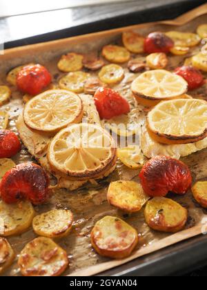 Filetto di merluzzo guarnito con timo, aglio e pomodori, preparazione di un piatto sano. Concetto di cibo sano Foto Stock