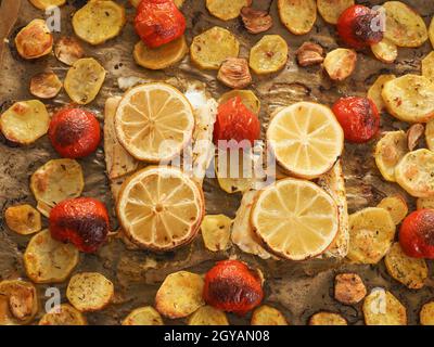 Filetto di merluzzo guarnito con timo, aglio e pomodori, preparazione di un piatto sano. Concetto di cibo sano Foto Stock