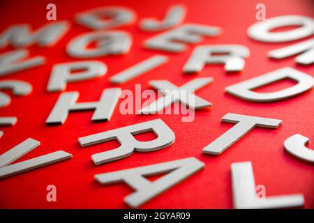 Le lettere piene miste impilano la foto in primo piano. Concetto di istruzione su sfondo rosso. Foto Stock