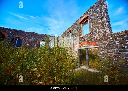 Interno di edificio senza tetto abbandonato con cielo completamente visibile e finestre e porte aperte ad elementi Foto Stock