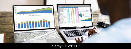 Dipendente di Spreadsheet Data Analyst che utilizza più schermi del computer Foto Stock