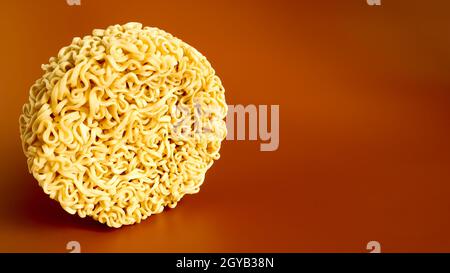 Pasta coreana istantanea a forma di cerchio su sfondo marrone. Vermicelli crudi, essiccati giallastro-bianchi, con lunghe linee rotonde e ritorti in dif Foto Stock