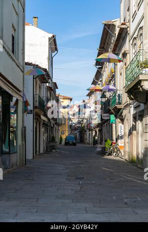 Ombrelloni colorati appesi su una strada tra splendidi edifici a Viana do Castelo, Portogallo Foto Stock