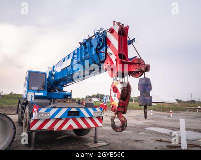 La gru per cantieri sta sollevando un cartello a LED vuoto su sfondo blu cielo per la nuova pubblicità Foto Stock