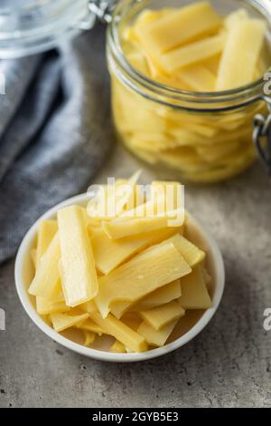 Germogli di bambù in scatola a fette in ciotola su tavolo da cucina. Foto Stock