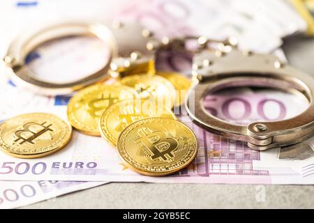 Banconote in euro, monete di bit e manette. Monete di criptovaluta. Foto Stock