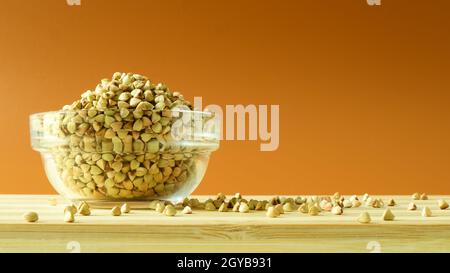 Grano saraceno verde in una ciotola trasparente di vetro su uno sfondo marrone. Alimenti sani. Cibo vegetariano non fritto, crudo e biologico. Il concetto di un sano e. Foto Stock