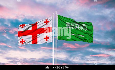 Georgia e Arabia Saudita due bandiere su flagpoli e blu cielo Foto Stock