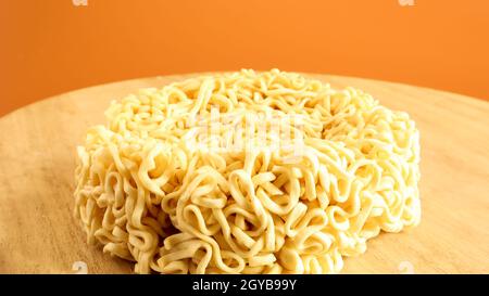 Pasta cruda istantanea su un piatto di legno con spazio per la copia per aggiungere testo sullo sfondo. Pasta, per la preparazione della quale basta versare bollitura Foto Stock