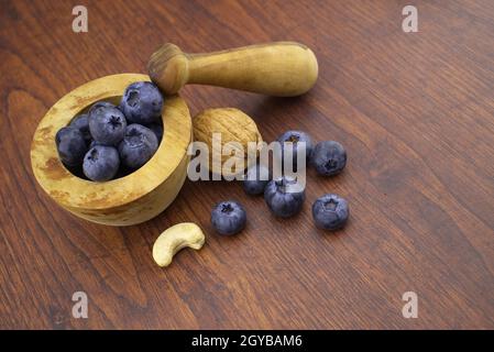 Pestello di legno e mortaio con noce, noce di anaceo e mirtilli freschi su un tavolo di legno con spazio di copia in un concetto di dieta sana e nutrizione, h Foto Stock