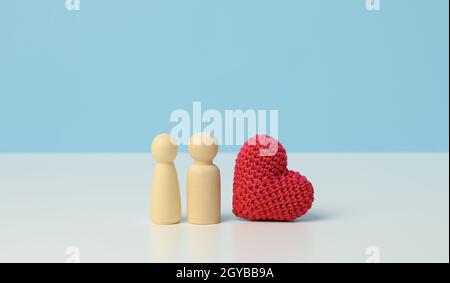 coppia di uomini di legno della sposa e dello sposo, cuore rosso, sfondo blu, concetto di amore e relazioni Foto Stock