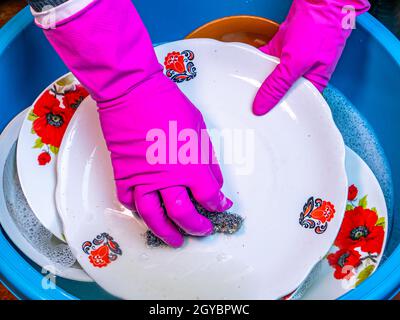 Lavare a mano gli utensili da cucina in una ciotola di plastica. Detergente per piatti. Lavastoviglie. Piastre di lavaggio a mano in un recipiente di plastica. Domestico. Governante. FEMA Foto Stock