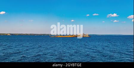 Piccola isola sull'orizzonte del mare sullo sfondo del cielo. Superficie dell'acqua. Stagcape. Fiumi e laghi. Fiume Dnepr. Litorale. Orizzonte nuvoloso. Foto Stock