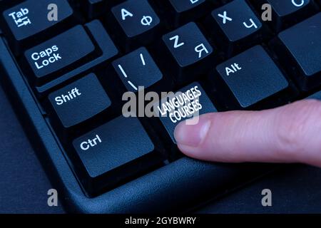Ispirazione che mostra segno Lingue Corsi, concetto di Internet set di classi o un piano di studio su una lingua straniera mani puntando computer pressing Foto Stock