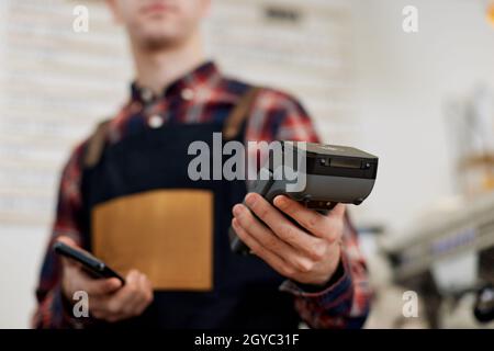 il barista dei dipendenti in grembiule ha un moderno terminale di pagamento bancario in caffetteria Foto Stock