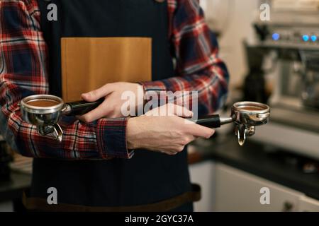 primo piano, barista in grembiule caffè macinato in caffè Foto Stock