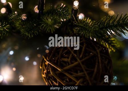 Scatto macro di una sfera di Natale fatta dai bastoni, attaccato ad una foglia dell'albero di Natale Foto Stock