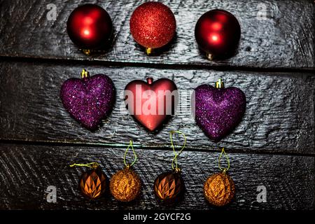 Primo piano di giocattoli colorati di Natale di diverse forme su una superficie di legno nero Foto Stock