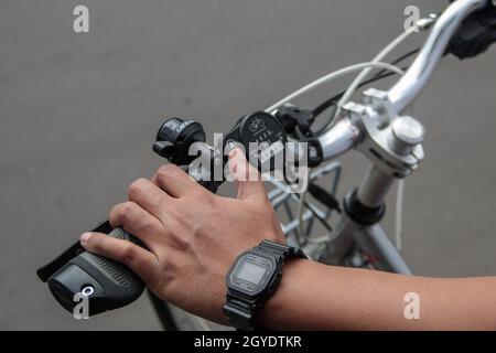 Bandung, Indonesia. 07 ottobre 2021. Un meccanico imposta la velocità su una bicicletta che è stata modificata in una bicicletta elettrica presso il laboratorio di Arusik Bikes a Bandung. L'innovazione di bicicletta standard che viene modificata utilizzando l'elettricità si basa su una dinamo aggiuntiva sulla ruota della bicicletta utilizzando un sistema di "pedalata assistita" e "gas throttle" che può durare fino a 70 chilometri. La batteria personalizzata "Arusik Bike" varia da 250 a 300 watt con un tempo di carica della batteria di 4 ore da zero a pieno. Credit: SOPA Images Limited/Alamy Live News Foto Stock