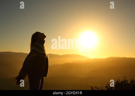 Profilo di una donna che respira aria fresca all'alba in montagna Foto Stock