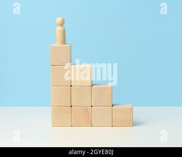 statuina di legno di un uomo su cubetti di legno. Il concetto di proposità, raggiungimento degli obiettivi, superamento degli ostacoli Foto Stock