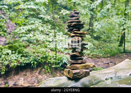 Alto stack di cairn di pietre su sfondo verde muto foresta Foto Stock