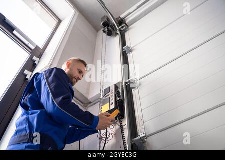 Installazione e riparazione della porta del garage a casa. Uomo appaltatore in casa Foto Stock