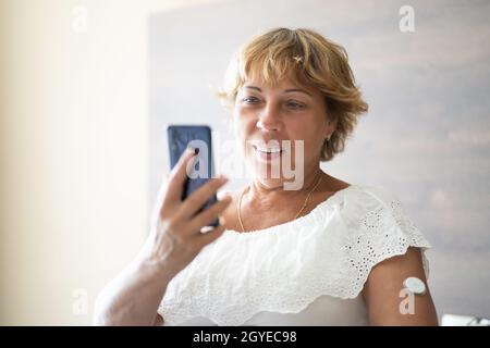 Donna che verifica il livello di glucosio con il monitoraggio continuo del glucosio su dispositivi mobili Telefono Foto Stock