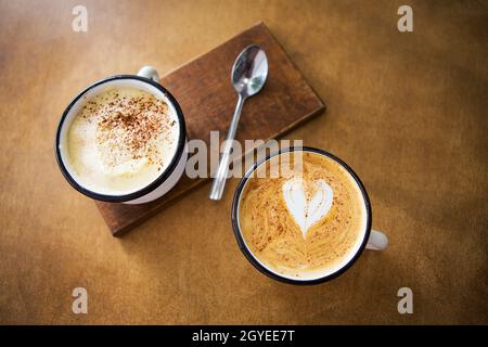 Due tazze di cappuccino e latte stand su di un tavolo di legno. Foto Stock