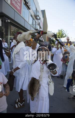 Il gruppo partecipa a una passeggiata Africana Healing intorno ad Harlem durante il giorno del festival African Heritage qui visto diretto verso l'up125th Street al Adam Clayton Powell NY state Building per African Square. Foto Stock