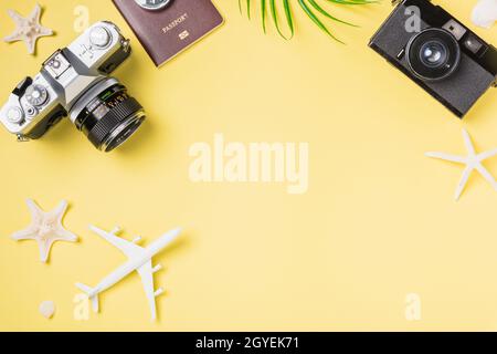 Flat Lay top view mockup retro fotocamera film, aereo, foglie, Starfish viaggiatore tropicale spiaggia accessori su uno sfondo giallo con spazio di copia, va Foto Stock