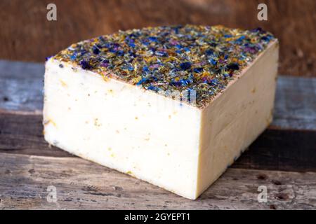 formaggio di montagna con fiori su legno Foto Stock