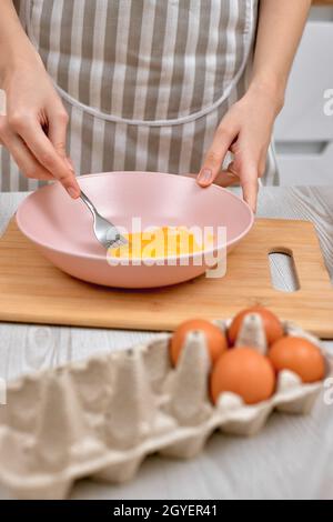 La donna batte le uova in una ciotola. Cucina casalinga a casa. Primo piano Foto Stock