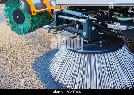 Combinazione di due spazzole spazzatrici stradali municipali in primo piano. Concetto di pulizia urbana di strada tutto l'anno. Foto Stock