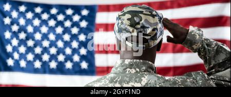 African American Army Soldier Saluting di fronte alla bandiera americana Foto Stock