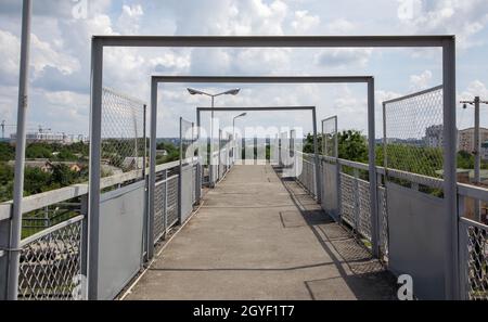 Ponte ferroviario con scalini, con scalini impressionanti in prospettiva. Attraversamento pedonale in alto. Ponte scale che collegano una piattaforma a un'altra presso Foto Stock