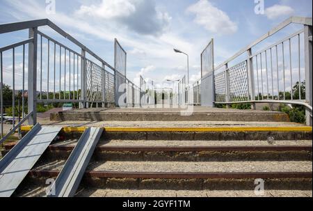 Ponte ferroviario con scalini, con scalini impressionanti in prospettiva. Attraversamento pedonale in alto. Ponte scale che collegano una piattaforma a un'altra presso Foto Stock