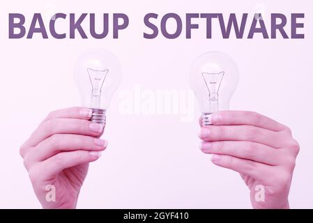 Scrittura visualizzazione testo Backup Software, Word per creare copie extra esatte di file o interi computer due mani tenere la lampada mostrare o presentare Foto Stock